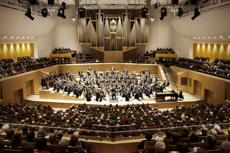Ein Orchester spielt vor Besuchern in der voll besetzten Konzerthalle.