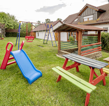 Ein Garten mit einem Pavillon und Kinderspielgeräten.