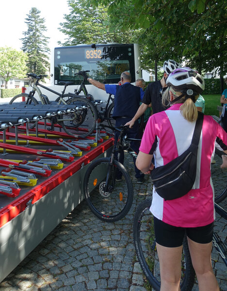 Eine Gruppe von Fahrradfahrern lädt die Fahrräder auf den Radanhänger eines Busses.