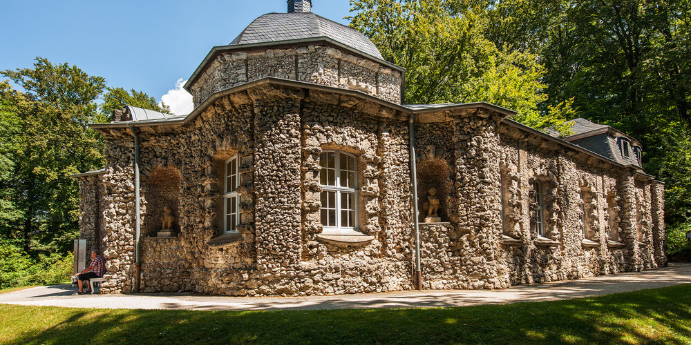 Ein aus kleinen Natursteinen gemauerter Bau mit weißen Sprossenfenstern.