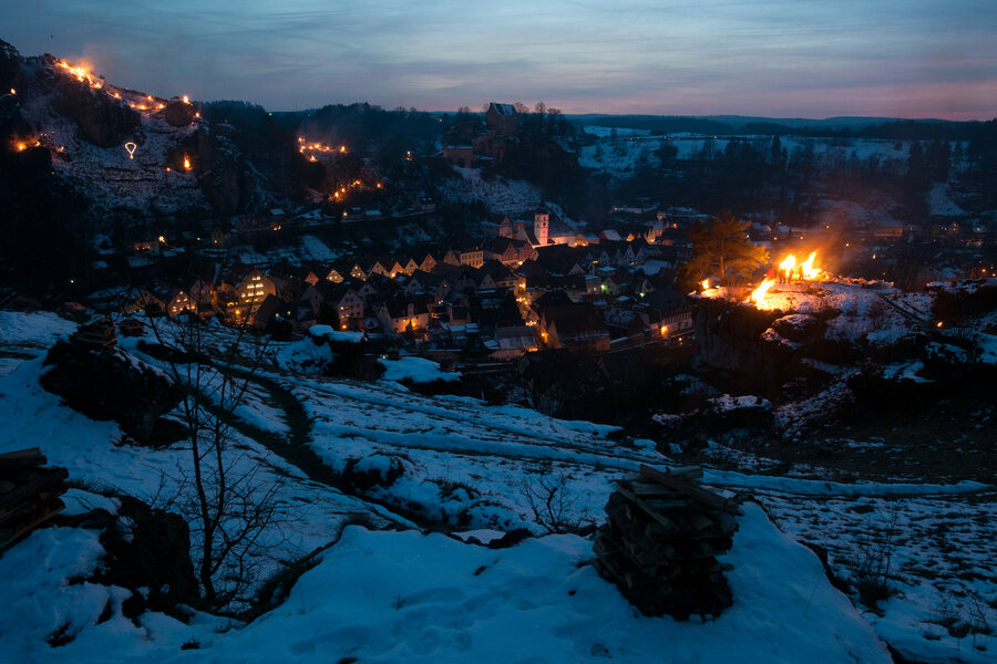 Bei Einbruch der Nacht erleuchtet im Tal der Ort. An den Felshängen beginnen Holzfeuer zu brennen.