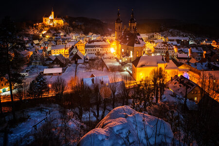 Nachtaufnahme der Burg und Kirche. Auf den Dächern des Ortes liegt Schnee. Die Beleuchtung der Straßen lässt das Bild weihnachtlich wirken.