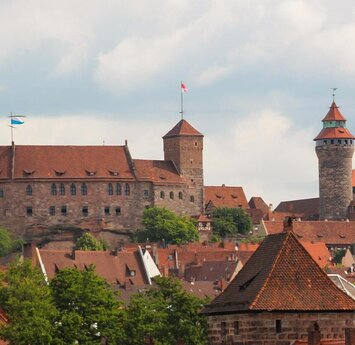 Eine große Burganlage mit Türmen und roten Dächer der Stadt.