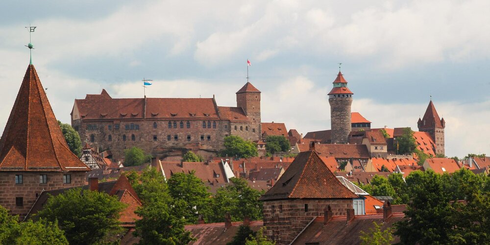 Eine große Burganlage mit Türmen und roten Dächer der Stadt.