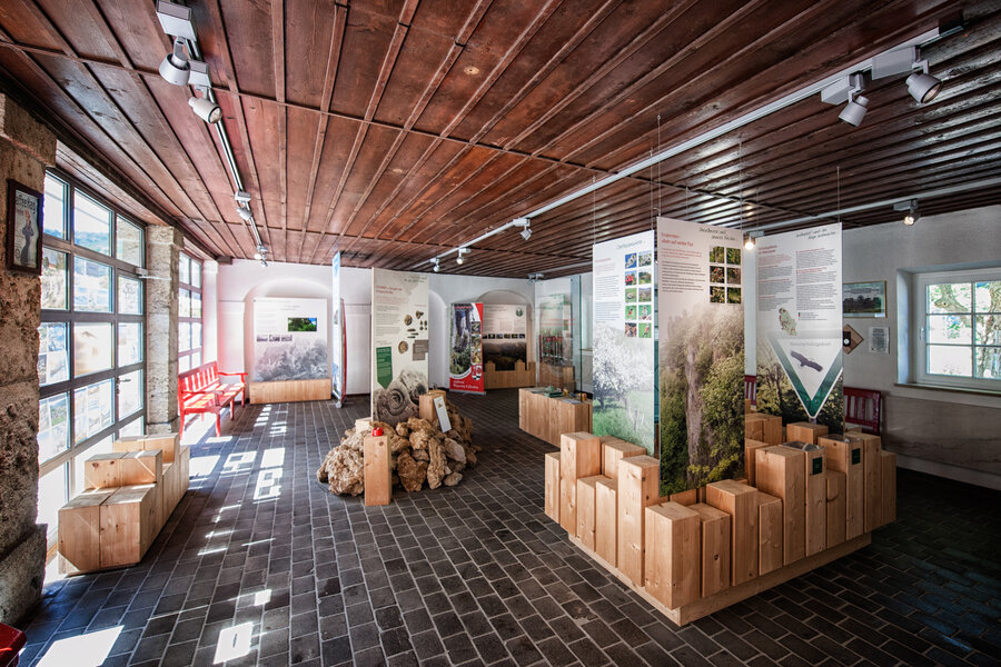 Ein Ausstellungsraum mit Holzelementen, zwischen denen auf Rollups Informationen stehen.