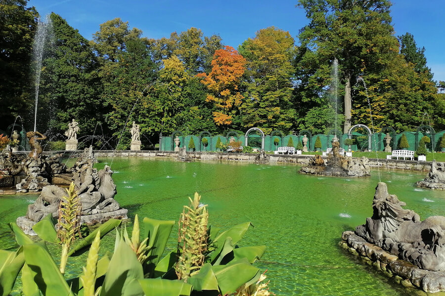 Wasserspiele mit verschiedenen Steinfiguren. Das Wasser leuchtet grün.