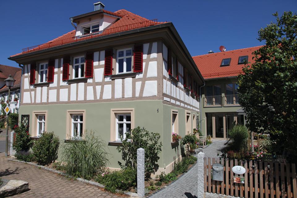 Ein grün-weißes Fachwerkhaus mit roten Dach.